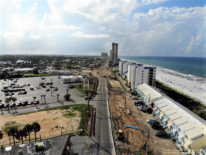 Aerial view of Front Beach Road construction on segment 3 of CRA, with blue sky, emerald water and buildings and road construction