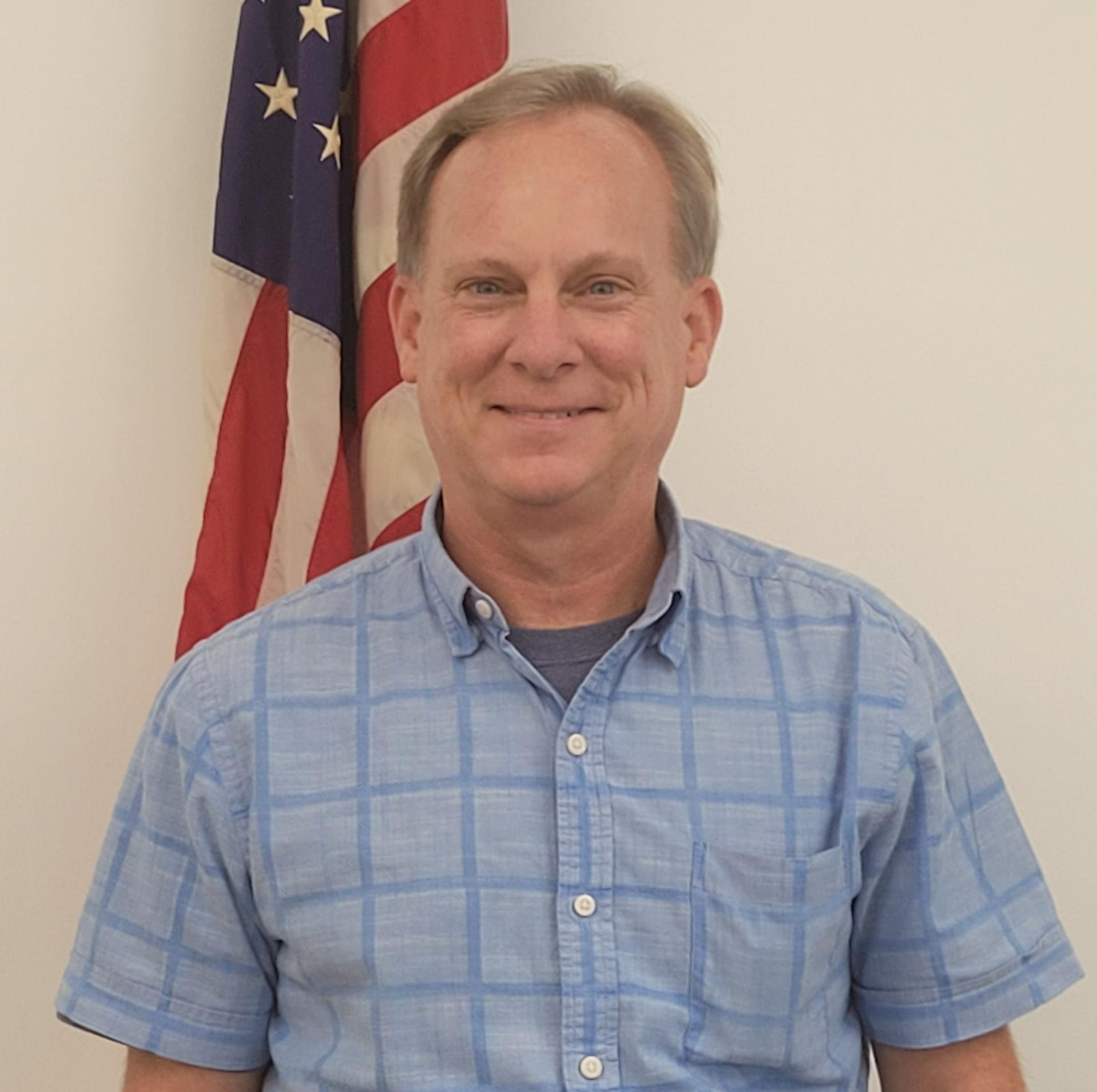 Mel Leonard, Building & Planning Director standing in front of American Flag